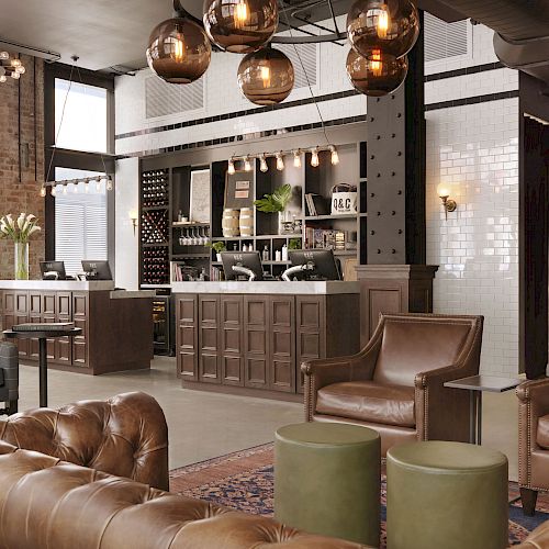 The image shows a modern, cozy cafe with leather seating, a counter with coffee machines, pendant lights, and a warm, inviting atmosphere.