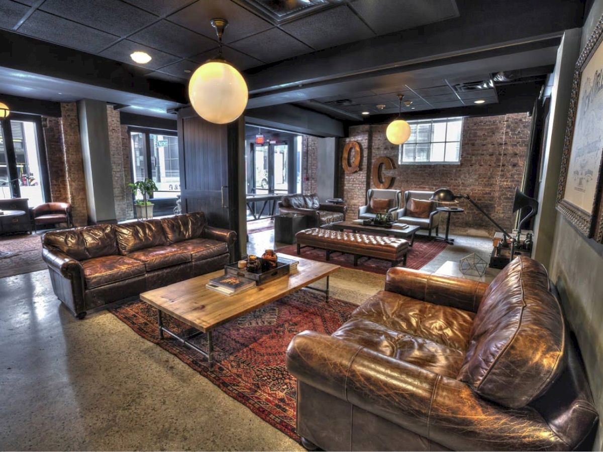 A modern lounge with leather sofas, wooden coffee tables, and industrial-style decor, featuring large windows and warm lighting, creating a cozy atmosphere.