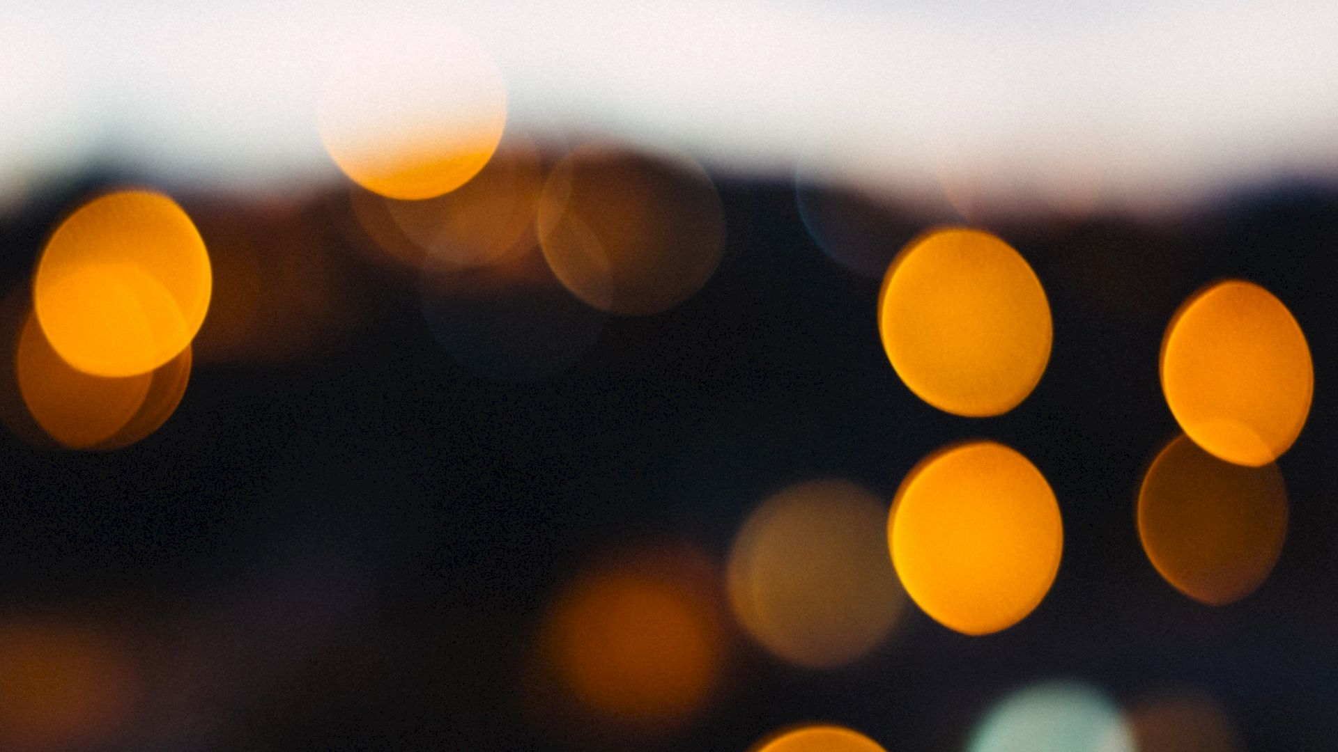 The image shows a bokeh effect with circular orange and yellow lights against a dark background, creating an abstract and blurred aesthetic.