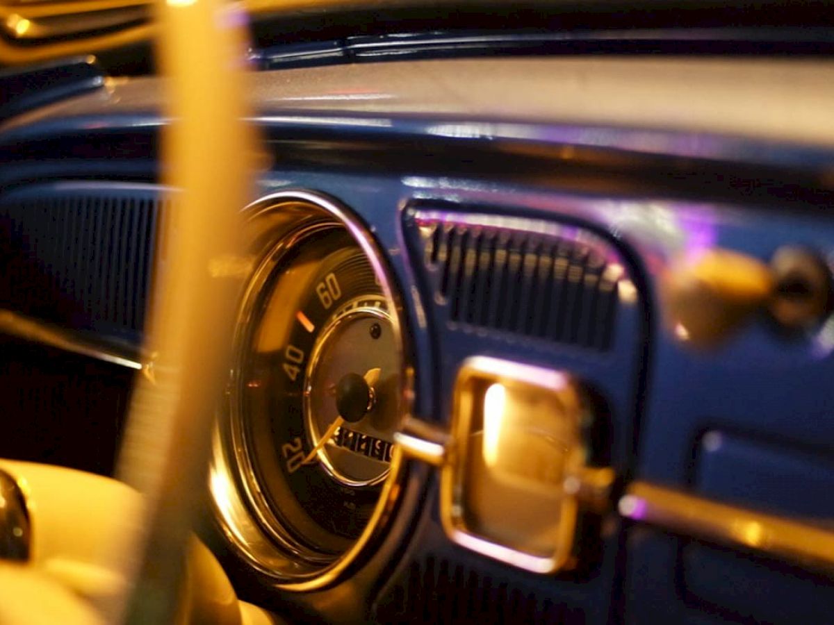 This image depicts the dashboard of a classic car, featuring a speedometer that shows speeds in kilometers per hour, up to 120 km/h, with stylish lighting.