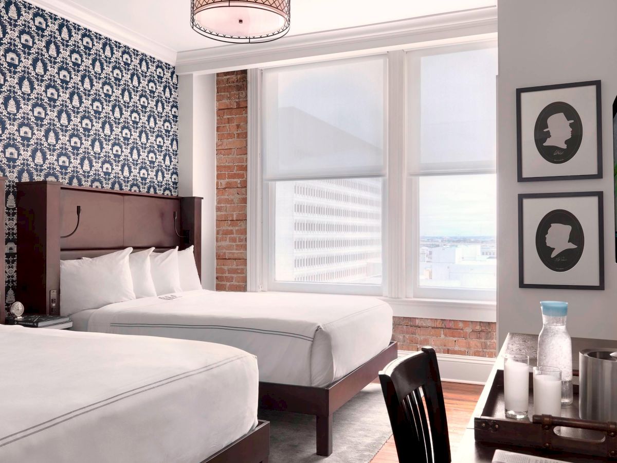 A modern hotel room features two beds, a patterned blue wallpaper, a flat-screen TV, and a well-lit window with city views to create a relaxing ambiance.