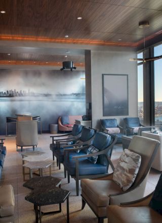 A modern lounge area with comfortable seating, large windows offering a city and water view, and a wall mural depicting a skyline ends the sentence.