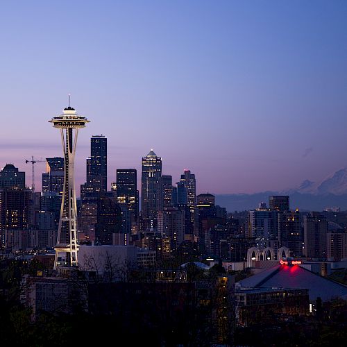 The image features the Seattle skyline at twilight, with the Space Needle prominently visible and Mount Rainier in the background.